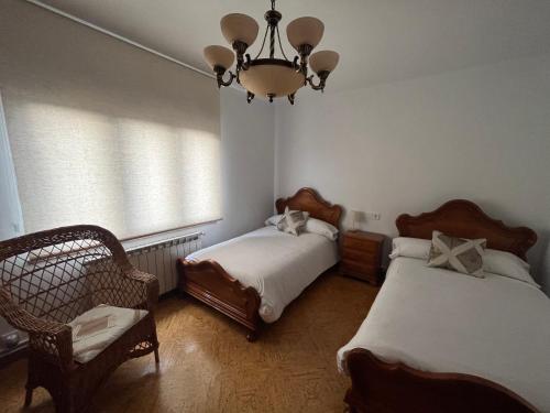 Un dormitorio con dos camas y una lámpara de araña. en Vivienda Vacacional Los Campones, en Berrón