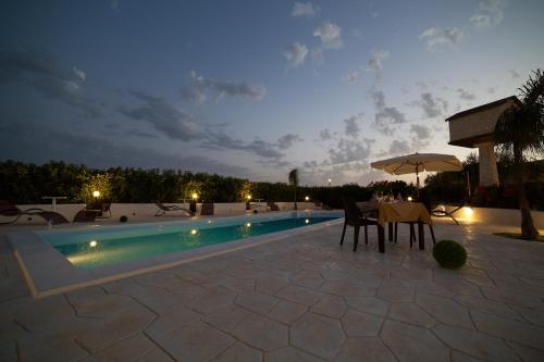 a patio with a table and chairs next to a swimming pool at Le Zarafe in Caltabellotta