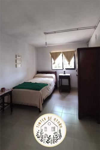 a bedroom with a bed and a table and a window at Tintes de otoño in Mina Clavero