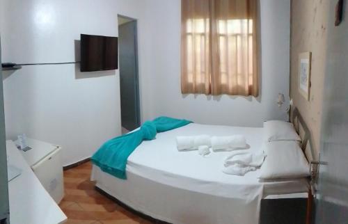 a bedroom with a white bed with towels on it at Pousada aconchego da Serra Serra do cipó in Santana do Riacho