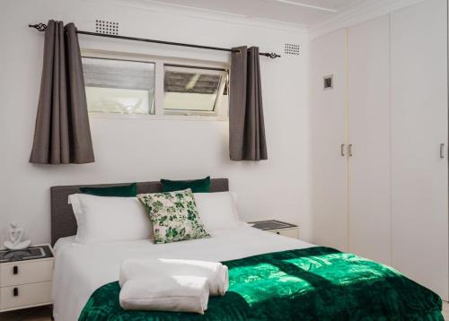 a bedroom with a green and white bed with a window at Mindful Escape Cottage in Heathfield