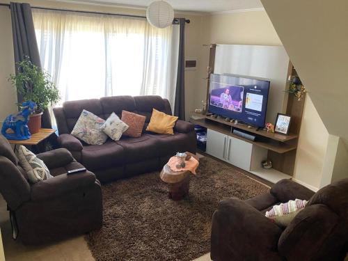 a living room with couches and a flat screen tv at Habitación cama 2 P, en zona residencial cerca Mall plaza, UCM, Casino Talca in Talca