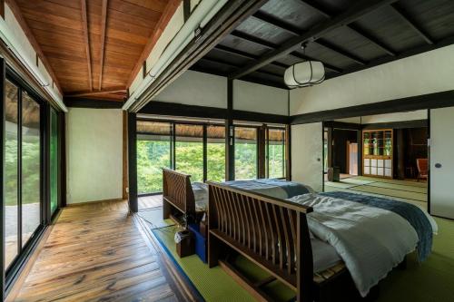 a bedroom with a bed in a room with windows at OMOYA総領 時を紡ぐ茅葺きの宿 - Thatched inn that spins time - Supported by COCOSTAY in Shōbara