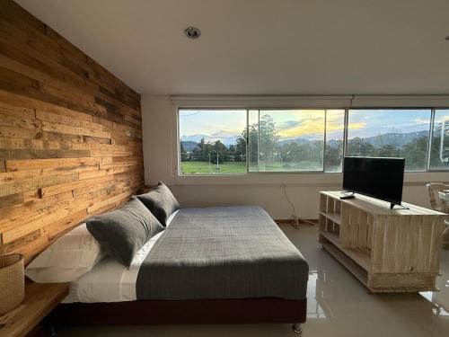 a bedroom with a wooden wall with a bed and a desk at Countryside apartment in Rionegro