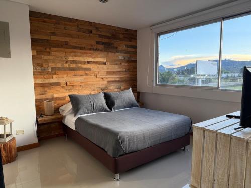 a bedroom with a bed with a wooden accent wall at Countryside apartment in Rionegro