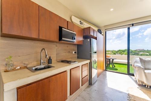 a kitchen with wooden cabinets and a large window at Private Jacuzzi, Starlink, Golf-View Terrace - Puerto Aventuras in Puerto Aventuras