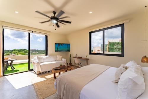 a bedroom with a bed and a couch and windows at Private Jacuzzi, Starlink, Golf-View Terrace - Puerto Aventuras in Puerto Aventuras