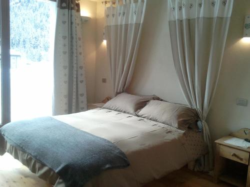 a bedroom with a bed with curtains and a window at La Niche B&B in La Thuile