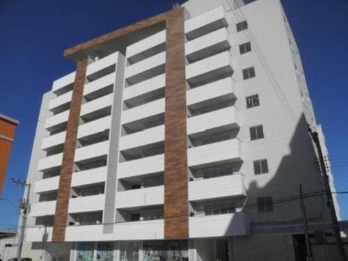a tall white apartment building with a brick at Apartamento aconchegante a 100 metros da praia! in Porto Belo