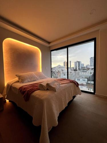 a bedroom with a large bed with a large window at Apartamento en Roma Norte, Estilo mas Comfort in Mexico City