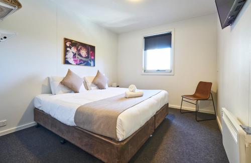 a bedroom with a large bed and a chair at The Island Accommodation in Phillip Island