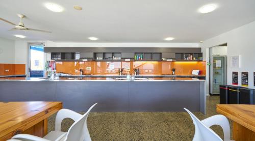 a large kitchen with orange cabinets and white chairs at The Island Accommodation in Phillip Island