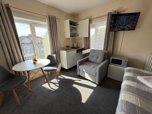 a small living room with a bed and a table at Southsea 2nd Floor Studio Apartment, Free Private Parking in Portsmouth