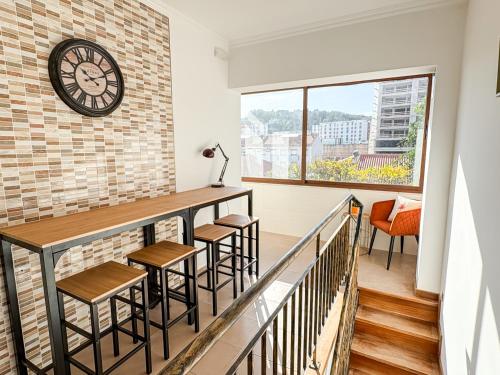 a balcony with stools and a clock on a brick wall at VT Guest House in Setúbal