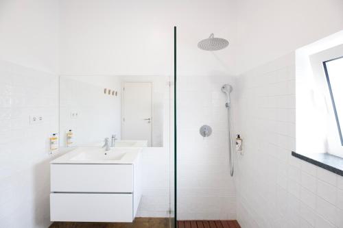 a white bathroom with a sink and a shower at Casa do Pisão - Cosy and Modern Two-Bedroom Townhouse in Angra do Heroísmo
