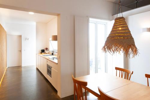 a kitchen and dining room with a table and a chandelier at Casa do Pisão - Cosy and Modern Two-Bedroom Townhouse in Angra do Heroísmo