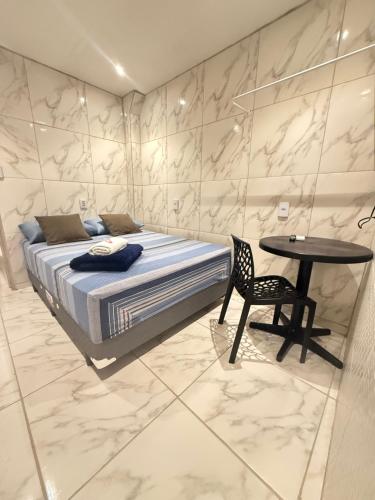 a bedroom with a bed and a table with a chair at Cantinho aconchegante - Quarto 05 AR-condicionado in Bayeux