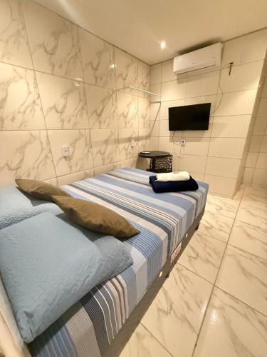 a bedroom with a bed and a tv on a wall at Cantinho aconchegante - Quarto 05 AR-condicionado in Bayeux