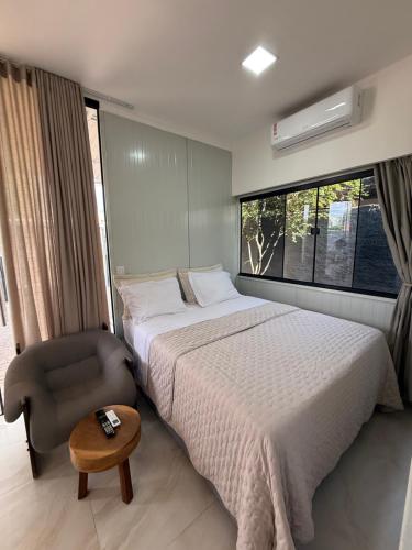 ein Schlafzimmer mit einem Bett und einem Stuhl und einem Fenster in der Unterkunft Studio Laranjeira in Palmas