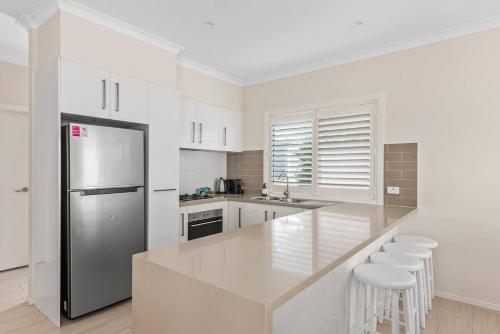 a white kitchen with a counter and a refrigerator at Sunny Townhouse in Huskisson