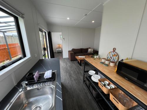 a kitchen with a sink and a couch in a room at Cosy Rotorua Retreat By Aotearoa Escapes in Koutu