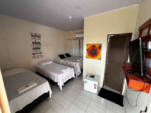 a small room with two beds and a tv at Pousada Maré do Cerrado in Mateiros