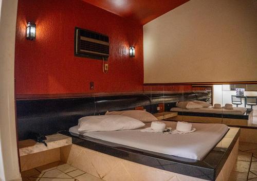 two beds in a room with red walls at Motel das Nações in Bauru