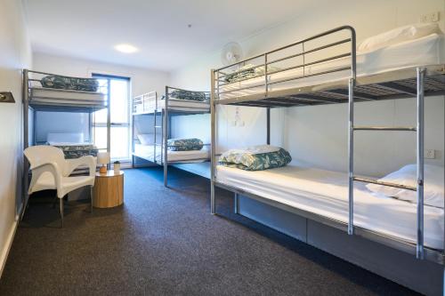 a dorm room with three bunk beds and a chair at The Island Accommodation in Phillip Island