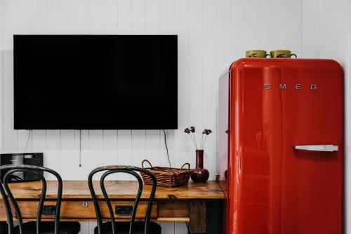 a red refrigerator sitting next to a wooden table with chairs at Union Street - Central Castlemaine Pad in Castlemaine