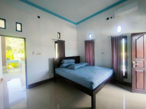 a bedroom with a bed with blue sheets and windows at Pondok Segara Guesthouse in Padangbai