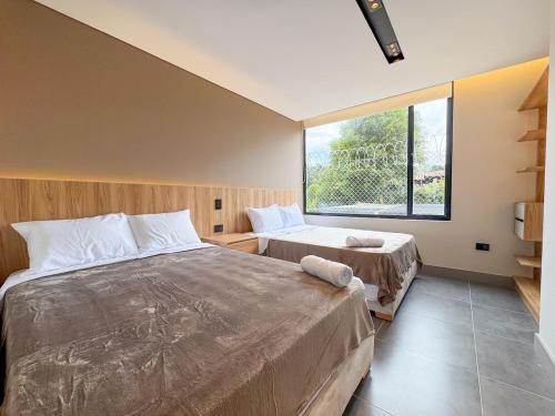 a bedroom with two beds and a large window at Apartamento de lujo a 3 minutos del Aeropuerto JMC 102 in Rionegro