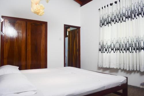 a white bedroom with a bed and a window at My Place Hikkaduwa in Hikkaduwa