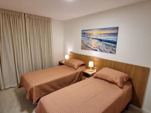 a hotel room with two beds and a picture of the ocean at Apartamento Frente pra Praia em Resort in Arraial do Cabo