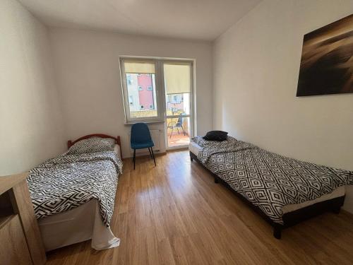 una stanza con due letti e una sedia di Apartament #SIKORSKIEGO FV PARKING BALKON a Rzeszów