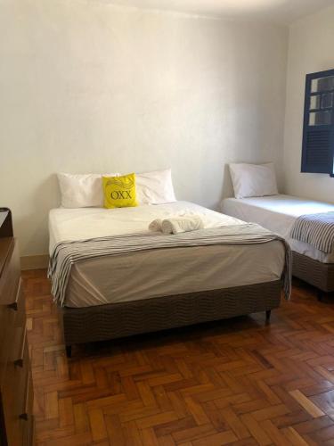 een slaapkamer met twee bedden met een geel kussen bij Oxx in Congonhas