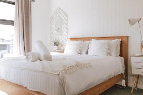 - une chambre avec un grand lit blanc et des oreillers blancs dans l'établissement B e a c h H o u s e X I V, à Bicheno