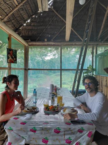 a man and woman sitting at a table with food at Amazon tucuxi in Islas Timicuro