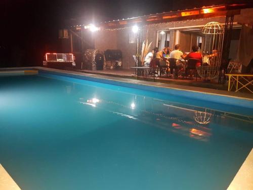a swimming pool at night with people sitting at a restaurant at La Morada de sus Sueños Caeiro in Bialet Massé