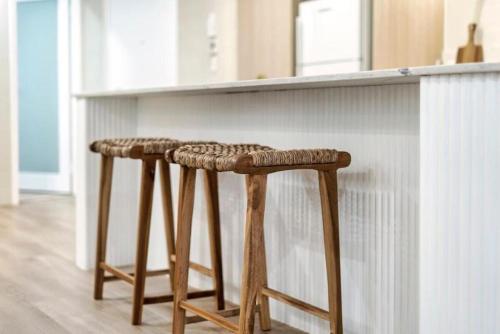 a pair of wooden stools next to a kitchen counter at Luxury Living on Monaco Riverfront - Hosted by Coastal Letting Co. in Gold Coast