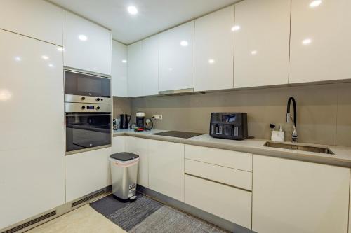 una cucina bianca con mobili bianchi e un lavello di JolikaS House Heated Pool and EV point a Fernão Ferro