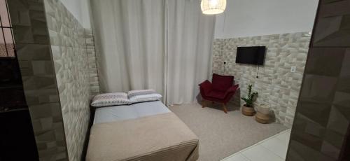 een slaapkamer met een bed en een rode stoel bij Casa No Centro de Angra da Glaucia in Angra dos Reis