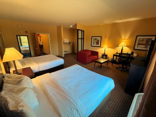 a hotel room with two beds and a desk at Brunswick Suites Golden Isles Gateway I-95 in Brunswick