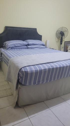 a large bed with a blue and white striped comforter at Ultimate Chill 1BDR Browns Town #1 in Browns Town