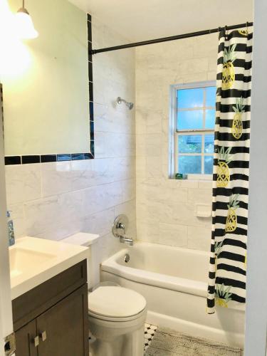 a bathroom with a white tub and a toilet and a sink at Pineapple Cottage 2 bedroom in Jensen Beach