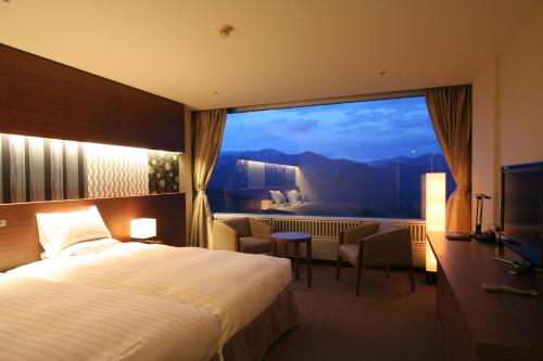 Cette chambre comprend un lit et une grande fenêtre. dans l'établissement Minakami Kogen Hotel 200, à Minakami