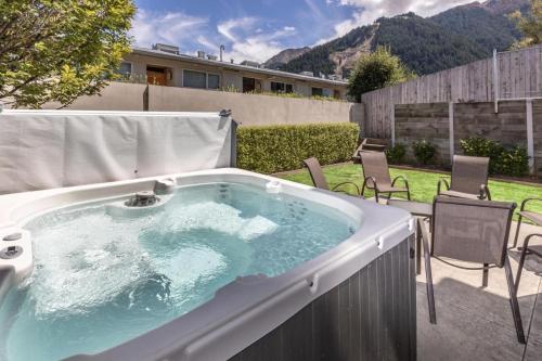 5 bedroom modern apartment in the heart of QT في كوينزتاون: حوض استحمام ساخن على فناء مع كراسي في الفناء