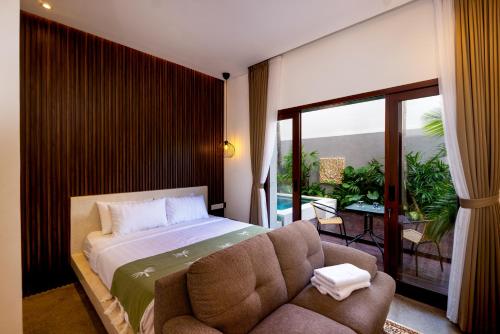 een slaapkamer met een bed, een bank en een balkon bij Harmoni Lane Studios in Seminyak