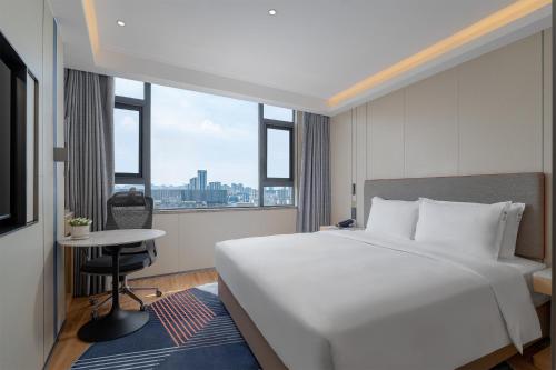 Un dormitorio con una gran cama blanca y una ventana. en Holiday Inn Express Kunming Railway Station by IHG, en Kunming
