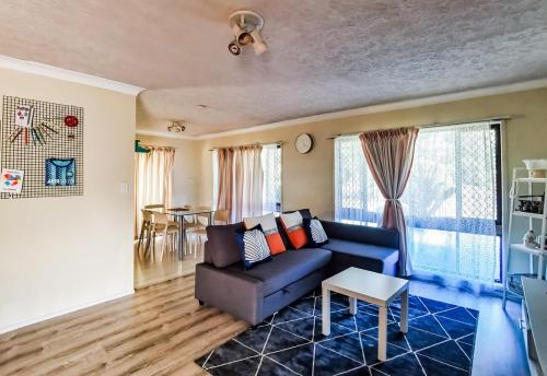 a living room with a blue couch and a table at Entire independent 3 bdrm house in Algester