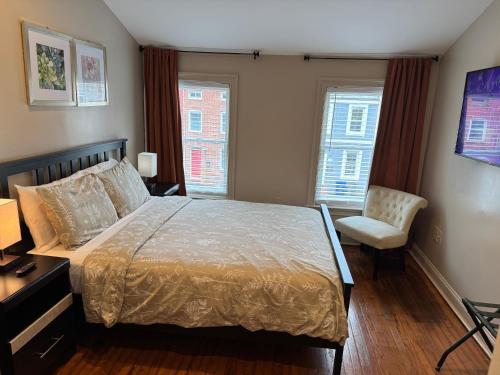 a bedroom with a bed and a chair and two windows at Townhouse in Baltimore in Baltimore